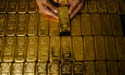 Personne déposant un lingot d'or dans une réserve bien garnie en métaux précieux