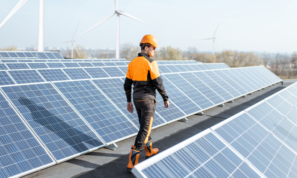 Worker on a solar station equipped with wind turbines
