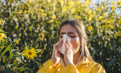 Portrait of a young woman surrounded by flowers and developing an allergic reaction